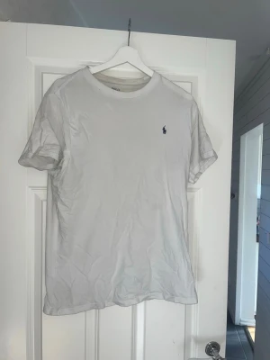 Vit t-shirt från Ralph Lauren - Klassisk vit t-shirt från Ralph Lauren med rund hals och liten broderad logga på bröstet. Enkel och stilren design, perfekt till jeans eller shorts. Tillverkad i mjuk bomull för skön känsla hela dagen. Nypris- 500