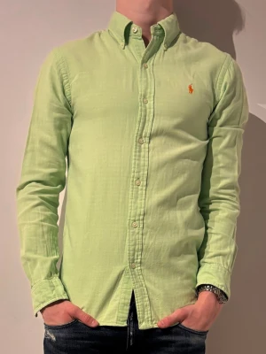 Ljusgrön skjorta från Ralph Lauren - Snygg ljusgrön skjorta från Ralph Lauren💯 med klassisk button-down krage och broderad logga i orange på bröstet☀️. Skjortan har lång ärm, knappar framtill och är tillverkad i ett mjukt bomullstyg.✌️ Perfekt för en fräsch och stilren look. Storlek S modellen är 180 och väger 70kg.💯 hör av er vid minsta fråga eller fundering💯💯✌️😊