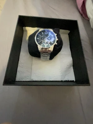 Silverfärgad Invicta kronografklocka - Stilren kronografklocka från Invicta med silverfärgad länkarmband i metall. Urtavlan är mörk med flera små ur och tydliga siffror, vilket ger en modern och sportig känsla. Perfekt accessoar för dig som gillar detaljer och snygg design.