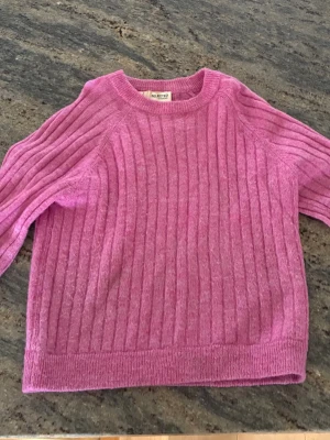 Rosa ribbstickad tröja från Selected  - Säljer en rosa ribbstickad tröja från Selected med rund halsringning och långa ärmar. Tröjan har en avslappnad passform och är tillverkad i ett mjukt stickat material som passar perfekt för kyligare dagar.