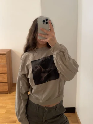 Beige sweatshirt från Stay med tryck (100% bomull) - (100% BOMBULL) passar s/xs) Säljer en beige sweatshirt från Stay med ett stort svart tryck framtill. Tröjan har rund halsringning, långa ärmar och avslappnad passform. 