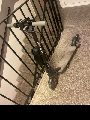 Navee easyride 20 - Elektrisk scooter i svart med gråa handtag från Ninebot. Scootern har robust ram, stora hjul och en bred ståplatta. Perfekt för att ta sig fram snabbt i stan. Laddningsuttag och bromsljus bak.