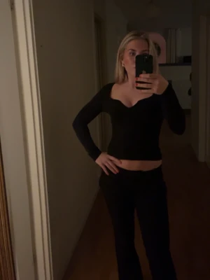 Svart croppad v-ringad topp - Säljer en svart croppad topp med v-ringad hals och långärmade ärmar. Perfekt för dig som gillar en enkel och stilren look. Toppen har en tight passform och är riktigt snygg att matcha med jeans eller kjol.