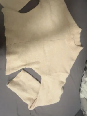 Beige stickad tröja med rund hals - Mysig beige stickad tröja med rund hals och långa ärmar. Tröjan har en enkel, clean design med ribbade muddar vid halsen och ärmsluten. Perfekt för lager på lager och passar till det mesta i garderoben.