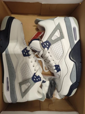 Vill bli av med helt nya Air Jordan 4 White Oreo sneakers - Snygga Air Jordan 4 sneakers. Jag köpte dem billigt till min tjej men hon gillade dem inte så de är helt nya, hon provade dem inte ens. De är i väldigt bra kvalitet med vitt läder med grå och marinblå detaljer samt specklad grå sula. Klassisk meshpanel på sidorna och Jumpman-logga på plösen. Skorna har en chunky siluett och coola plastdetaljer vid snörningen. Jag kan skicka med extra snören i nån färg om det önskas. 