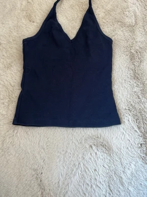 Mörkblå linnetopp från Stradivarius - Snygg mörkblå linnetopp från Stradivarius med smala axelband och v-ringad hals. Perfekt till sommaren och enkel att matcha med olika stilar. Tillverkad i mjuk bomull för en bekväm känsla. assnygg på! säljer pga att jag har en i en annan färg redan❤️sänker pris vid snabbt köp