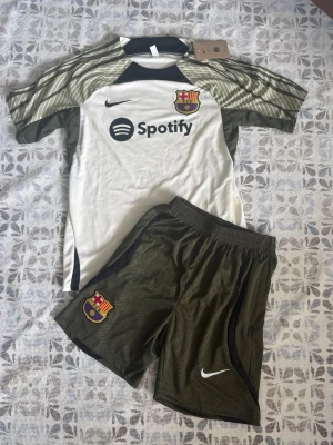 FC Barcelona matchställ Nike grön/vit - FCB fotbollsträningsset i storlek S. Shortsen har fickor med dragkedjor. Helt nya och oanvända, perfekt till sommaren. Hör gärna av vid frågor!