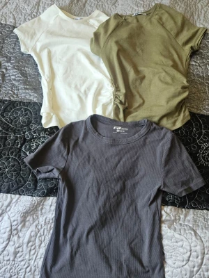 3-pack t-shirts från FB Sister - Tre stilrena t-shirts från FB Sister i storlek M. En vit, en olivgrön och en mörkgrå ribbad t-shirt. Alla har rund halsringning och korta ärmar. Perfekta basplagg till garderoben och passar till många olika outfits.
