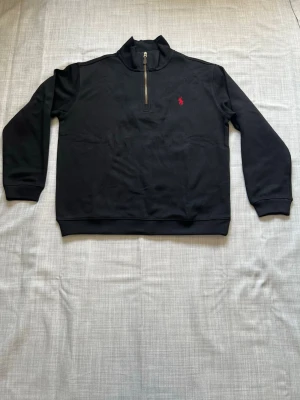 Ralph lauren quarter zip svart strl L - Säljer en helt ny Ralph Lauren quarter zip i svart färg. Väldigt clean och stilren modell som passar perfekt till vardag, skola eller sommar kvällar. Sjukt lätt att matcha och en av de mest populära Ralph Lauren modellerna just nu. Oanvänd och i nyskick i storlek L. Snabb frakt och paketpris finns vid köp av flera plagg