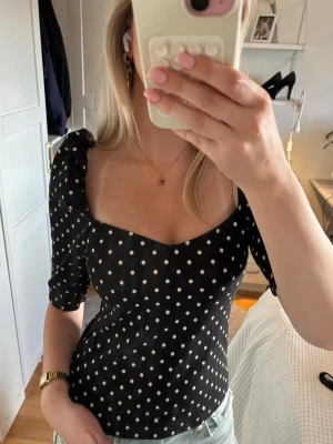 Svart prickig topp med puffärm - Trendig svart topp med vita prickar och snygg v-ringning, Toppen har puffiga halvlånga ärmar. Tröjan har inga defekter, bara att höra av sig vid frågor 💗💗