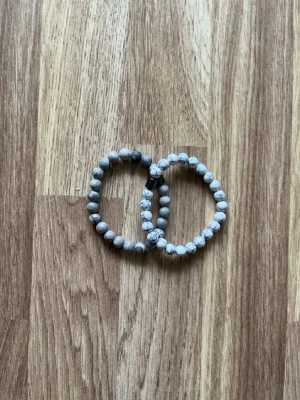 Två stycken armband  - Säljer två fina armband – ett grått och ett vitt. De passar perfekt tillsammans och är en snygg accessoar till sommaren. Båda säljs tillsammans för endast 25 kr. I mycket bra skick och skickas snabbt! 📦🚚