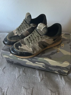 Valentino Rockrunners skor - Snygga sneakers från Valentino med camomönster i beige, svart och grå toner. Skorna har en låg silhuett, snörning och detaljer i mocka och mesh. Perfekta för dig som vill ha en unik och trendig look med exklusiv känsla.