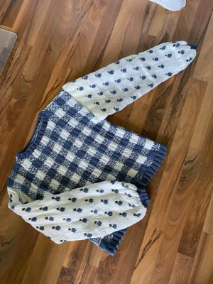 stickad tröja med blåbär - Unik stickad tröja i blått och vitt med rutigt mönster på kroppen och små blåbär på ärmarna. Tröjan har rund hals och ribbstickade muddar. Perfekt för dig som gillar retrovibbar och vill sticka ut med din stil. Väldigt lantlig och Cottagecore. Stickad i ett bomullsgarn så den är härlig att ha nu på sommaren!    Ena ärmen har två olika garn eftersom det ena tog slut så det är en liten nyansskillnad men det syns inte jättemycket 💕☀️ oversized stil