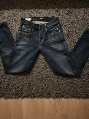 Replay anbass - Snygga mörkblå jeans från Replay med klassisk femficksmodell och kontrastsömmar. Jeansen är i passformen slimfit.  Tillverkade i denim med stretch för extra komfort. Perfekta för en trendig och avslappnad stil. Storlek 29/32. 