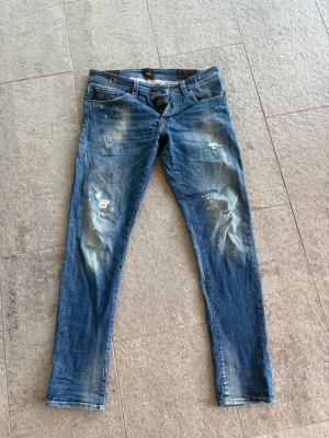TRAMMAROSSA JEANS - TRAMMAROSSA JEANS med slitningar, färgstänk och ljusa partier på benen. Jeansen har klassisk femficksdesign och låg midja. Perfekta för en avslappnad och trendig streetstil.