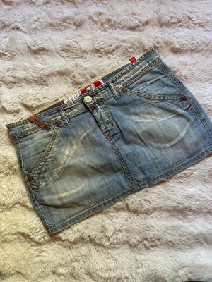 Y2K jeanskjol i ljus denim – unik detaljdesign - Snygg ljus jeanskjol med riktigt clean Y2K-look. Fina slitningar, detaljerade sömmar och broderade bakfickor som ger den där tidiga 2000-talsstilen ✨  * Märke: Take Two * Storlek: W30 * Färg: ljus denimblå * Skick: bra använt skick med snygg vintage/sliten wash  Passar perfekt till baby tee, linne eller oversized hoodie 🌟