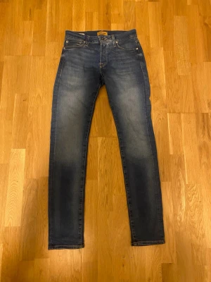 Blå slim fit jeans från Jack & Jones - Snygga blå slim fit jeans från Jack & Jones med klassisk femficksdesign och diskreta slitningar framtill. Jeansen har normal midja, smal passform och är tillverkade i stretchigt denim för extra komfort.