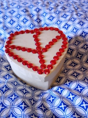 Hjärtask med röda pärlor - Säljer en vit hjärtformad ask dekorerad med röda plastpärlor i ett peace-märke på locket. Perfekt för småsaker, smycken eller som presentförpackning. Asken är gjord av kartong och har en unik, handgjord känsla.