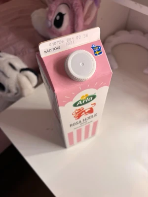 Arla Rosa Mjölk jordgubb 1L - En 1 liters förpackning Arla Rosa Mjölk med smak av jordgubb. Kartongen är rosa och vit med ränder och har en skruvkork. Perfekt för dig som gillar smaksatt mjölkdryck med en söt twist.