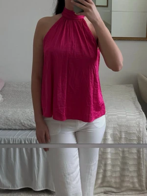 Rosa halterneck topp  - Superfin rosa halterneck topp i flowy modell med elegant fall. Väldigt somrig och feminin topp som passar perfekt till semester, middag, beach club eller fest. Knyts i nacken och sitter luftigt och fint