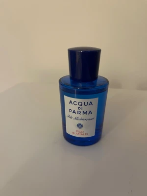 Acqua di Parma Fico di Amalfi parfym - Fräsch parfym från Acqua di Parma i serien Blu Mediterraneo, doften Fico di Amalfi. Flaskan är cylinderformad i klarblått glas med mörkblått plastlock och vit etikett med blå text. En elegant och stilren doft som ger medelhavsvibbar. 75 ml.