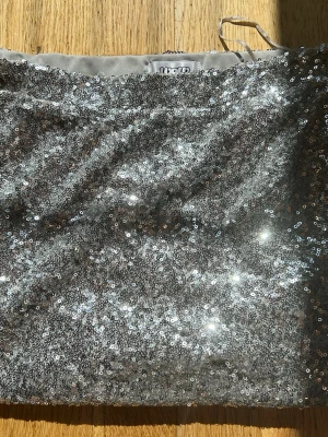 Silver paljett-tubtopp från WOW - Säljer en glittrig tubtopp från WOW i silver med massor av paljetter. Toppen är ärmlös och har en croppad passform som verkligen sticker ut. Perfekt för dig som vill ha en trendig och iögonfallande topp.
