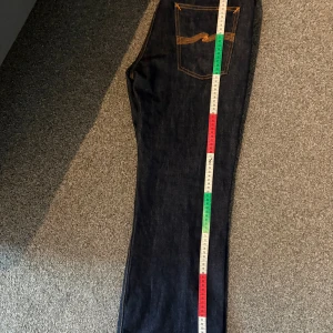 Nudie flare Glenn dry nostalgia - Ett par jättesnygga nudie jeans nästan helt nya använda 10 gånger kanske i mörkblått. Säljer på grund att de blivit för små så är inte rätt storlek som står på etikett men de är 107 cm långa o 47,5 cm breda