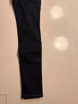Mörkblå raka jeans från Lee storlek W25 L31 - Snygga mörkblå jeans från Lee med klassisk rak passform och kontrastsömmar. Jeansen har fem fickor och är tillverkade i ett robust denimtyg. Perfekta för dig som gillar en tidlös och clean stil.