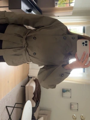 Kort khakigrön trenchcoat med knytskärp - Snygg kort trenchcoat i grön från Gina tricot. Den har inte kommit till användning så mycket, så väldigt fint skick!💚
