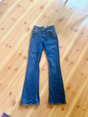 Mörkblå bootcut jeans - Snygga mörkblå bootcut jeans med klassisk femficksdesign och hög midja. Jeansen har utsvängda ben och är tillverkade i ett mjukt denimtyg. Perfekta för en trendig och avslappnad look.