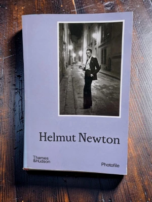 Fotobok Helmut Newton - En stilren fotobok från Thames & Hudsons Photofile-serie. Omslaget pryds av ett svartvitt foto taget av Helmut Newton, känd för sina ikoniska och konstnärliga bilder. Perfekt för dig som gillar fotografi och konst. Snygg bok att låta ligga framme som en del av inredningen.
