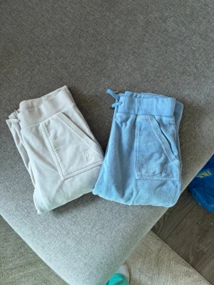 🩵🩶 Juicy Couture Velourbyxor (2 par) | XS 🩶🩵 - Säljer två superfina Juicy Couture velourbyxor i färgerna ljusblå och grå. Perfekt för dig som älskar den klassiska Juicy-stilen eller är ute efter bekväma och snygga loungebyxor. ✨  🧺 Skick: Bra använt skick. Normalt slitage förekommer men de har fortfarande mycket användning kvar.  🩵 1 par ljusblå 🩶 1 par grå.                                                                 🛍️ Kan även säljas separat vid intresse.  📸 Skickar gärna fler bilder, närbilder, mått eller passformsbilder om så önskas.