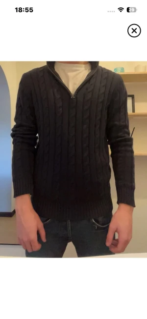 Mörkblå kabelstickad tröja Gant - Säljer en mörkblå kabelstickad tröja från Gant med halv dragkedja vid halsen. Tröjan har långa ärmar, ribbade muddar och klassisk kabelstickad struktur. Perfekt för lager på lager och en stilren look.