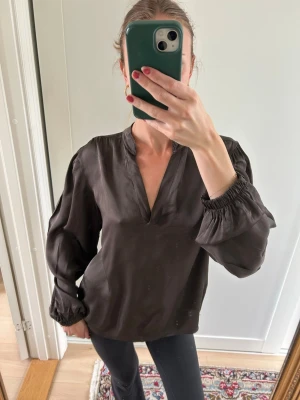 Mörkbrun sidenblus med v-ringning - Säljer denna super snygga och eleganta blusen! Perfekt för en finmiddag eller snygg vardagar outfit 🩷🕺🏽står inte storlek men gissar på S!