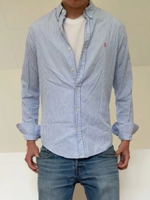 Ljusblå Randig Ralph Lauren Skjorta - Ljusblå Randig Ralph Lauren Skjorta i strl M men sitter som en S. Bra skick och hör gärna av er vid frågor elr funderingar!!