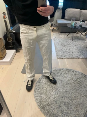 Vita raka jeans från Lee - Säljer ett par vita jeans från Lee med rak passform och klassisk femficksdesign. Jeansen har metallknapp och nitar, samt Lee-logga på linningen. Tillverkade i kraftigt bomullstyg som ger en clean och stilren look.