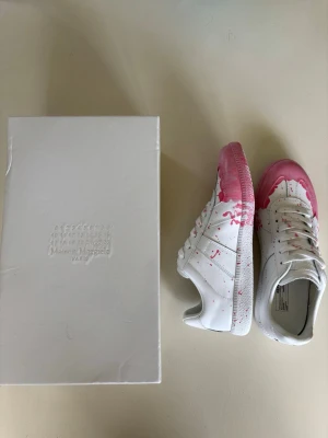 Maison Margiela  - Maison Margiela sneakers i vitt läder med snyggt färgstänk och detaljer. Kommer med originalkartong. Perfekt nu till sommaren. Hör gärna av er vid funderingar och köp.