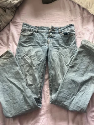 Ljusblå raka jeans - Säljer ett par ljusblå jeans med rak passform och klassisk femficksdesign. Jeansen har normal midja och stängs med dragkedja och knapp. Materialet är denim i bomull och färgen är snyggt tvättad för en avslappnad look.
