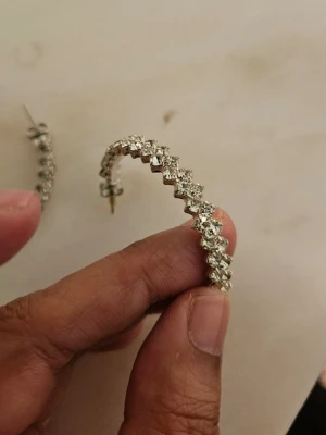 Silvriga creoler med gnistrande stenar - Säljer ett par silvriga creolörhängen med gnistrande, klara stenar runt hela ringen. Örhängena har en klassisk rund form och stängs med stift. Perfekta för dig som gillar att sticka ut med lite extra bling i vardagen. Har aldrig använt. Har allergi.  