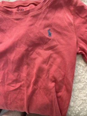 Corall tröja från Polo Ralph Lauren - Säljer en corall tröja från Polo Ralph Lauren med den klassiska blå loggan broderad på bröstet. Säljer då den är för kort för mig. Men den är väldigt skön och luftig.