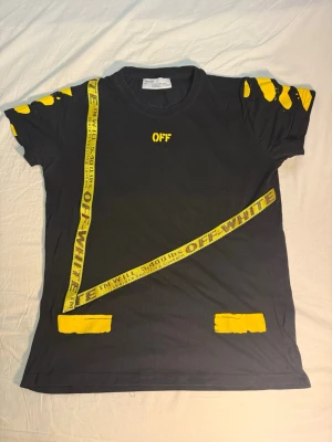 Off-White svart t-shirt med gula detaljer - Säljer en svart unik t-shirt från Off-White med gula tryck och grafiska detaljer både fram och bak. T-shirten har korta ärmar och coola Off-White-band och texten 'WHITE' på ryggen. Säljer även en klassisk svart calvin klein t-shirt med rött tryck och vit text. Båda kläderna är nästintill nyskick och på köpet ingår även en välanvänd röd armani exchange T-shirt med tydlig användning. (Se bild) Få allt för 250kr+frakt alt 100kr st STORLEKEN ÄR ABSOLUT M MEN GICK EJ ATT SKRIVA DET! 