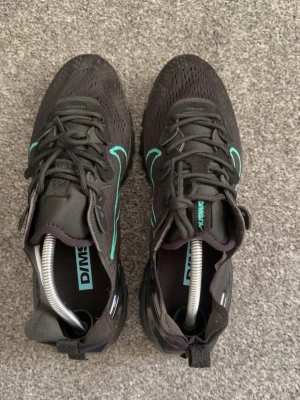 Nike svarta sneakers - Snygga svarta Nike x Off-White sneakers med turkosa detaljer och mesh-överdel. Skorna har en unik sula med vågig struktur och tydliga Off-White branding på plösen. Perfekta för dig som gillar streetwear och vill sticka ut med cool design.