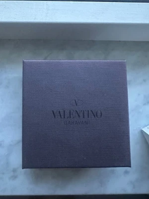 Valentino Garavani svart läderarmband - Snyggt svart läderarmband från Valentino Garavani med ikoniska nitar i metall. Armbandet har justerbart spänne och kommer i original ask och tygpåse. Perfekt accessoar för att lyfta din outfit med en edgy touch.