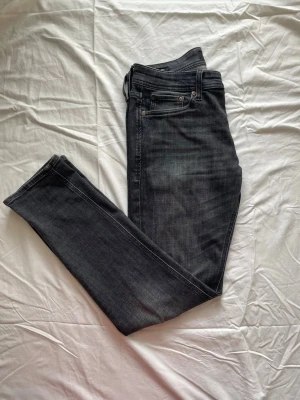Jack & Jones jeans  - Snygga svarta  jeans från Jack&jones  med klassisk femficksdesign och smal passform. Jeansen har en lätt tvättad look och är tillverkade i stretchigt denimtyg för extra komfort. Perfekta för en trendig och avslappnad stil.