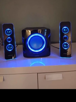 Andersson trådlöst högtalarsystem svart HELT NYA - Snyggt trådlöst högtalarsystem från Andersson med två smala satellithögtalare och en kraftfull subwoofer. Svart, glansig plast med blå LED-belysning runt elementen. Perfekt för att boosta ljudet till datorn eller TV:n. Modern design som passar in i de flesta rum. HELT NYA!