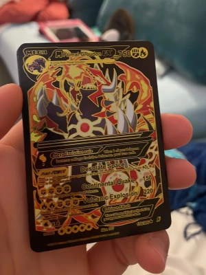 Pokémonkort Mega Primal Groudon EX - Säljer ett Pokémonkort Mega Primal Groudon EX med svart och guld design. Kortet har detaljer i rött, orange och gult samt holografiska effekter. Text och symboler är tryckta i guld. Perfekt för samlare eller Pokémonfans.