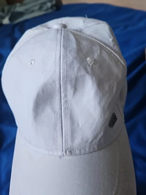 Vit keps från Hugo Boss - Snygg vit keps från Hugo Boss med klassisk böjd skärm och diskret logga på sidan. Tillverkad i bomullsmaterial som känns lätt och bekvämt. Perfekt accessoar för en clean och stilren look.