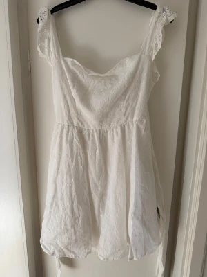 Studentklänning  - Söt vit kortklänning med broderade spetsdetaljer och breda axelband. Klänningen knytning i ryggen och är köpt till studenten men inte använd. 