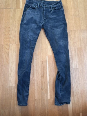 Mörkgrå slim jeans från Neuw - Säljer ett par mörkgrå slim fit jeans från Neuw, modell Lou Slim. Klassisk femficksdesign, normalhög midja och smal passform hela vägen ner. Snygg tvättad look och mjukt denimtyg som sitter skönt. Perfekta för en clean och modern stil. W31,L34