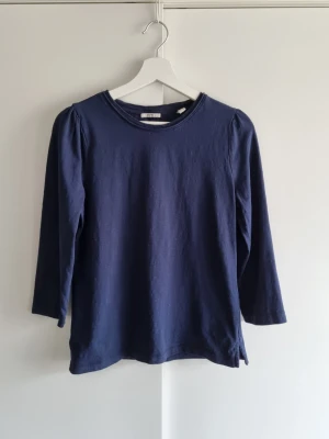 Mörkblå topp Esprit M - Marinblå topp från Esprit med rund halsringning och trekvartsärmar. Tillverkad i mjukt bomullsmaterial och har diskreta puffdetaljer vid axlarna för en trendig look. Perfekt skick.